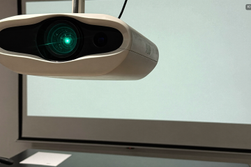 Beamer und Leinwand in einem Tagungsraum als Teil der Tagungstechnik